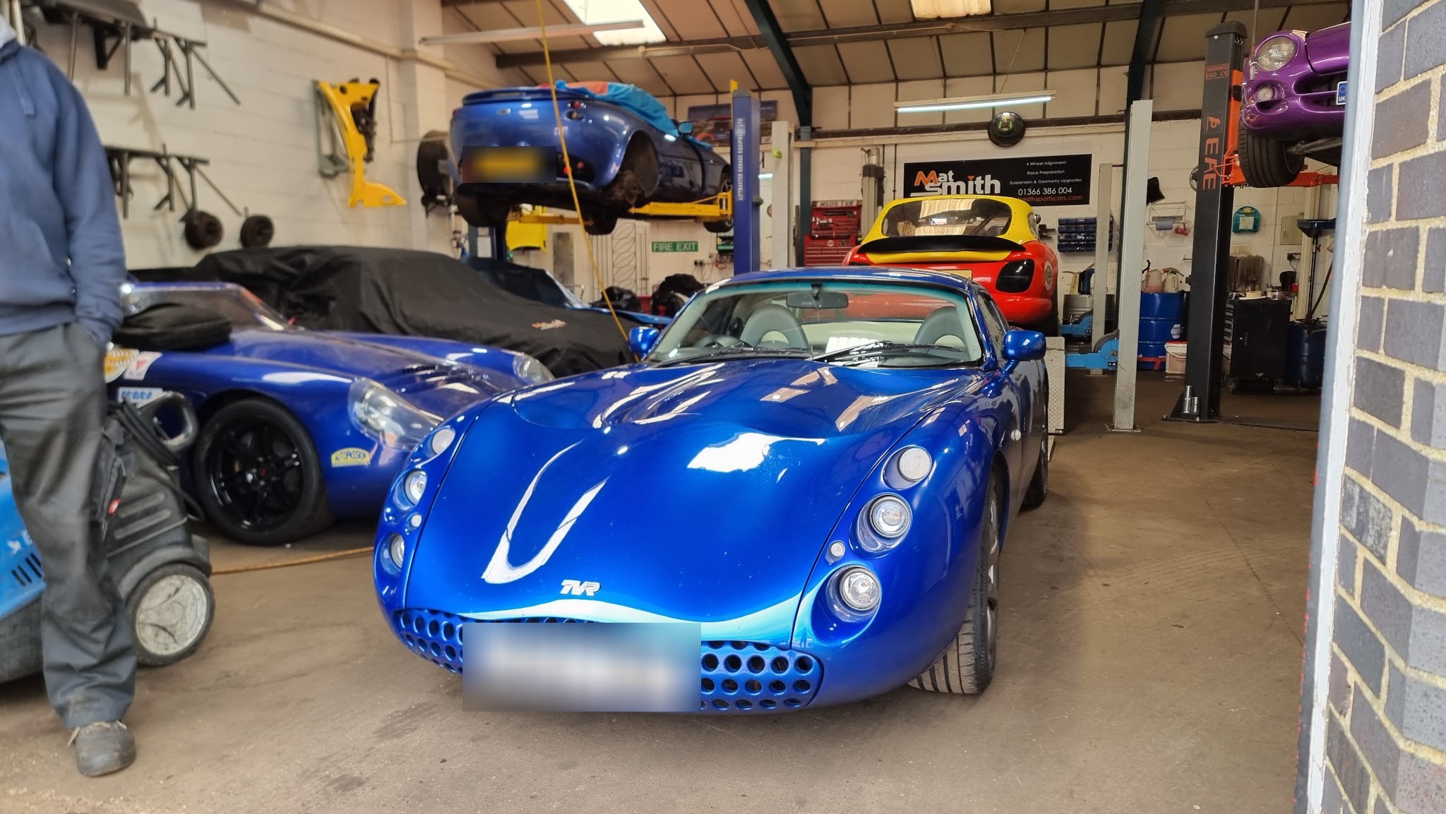 Inside the workshop: a blue TVR Tuscan in the doorway and cars up on the lifts