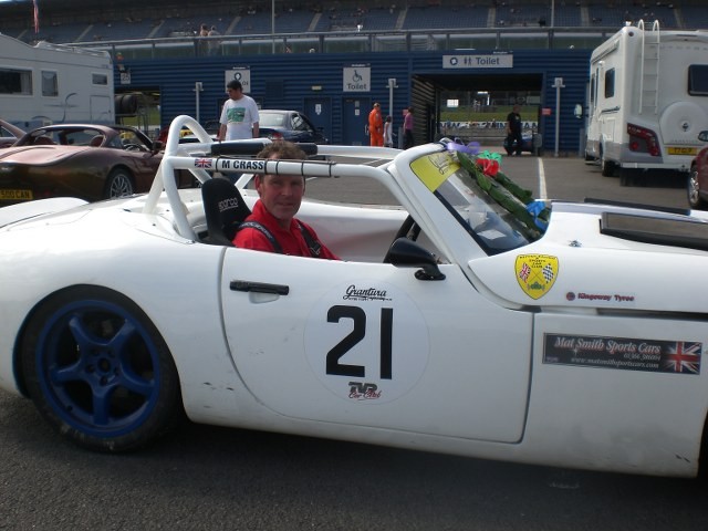 A white race car in a race paddock with a Mat Smith Sports Cars sticker