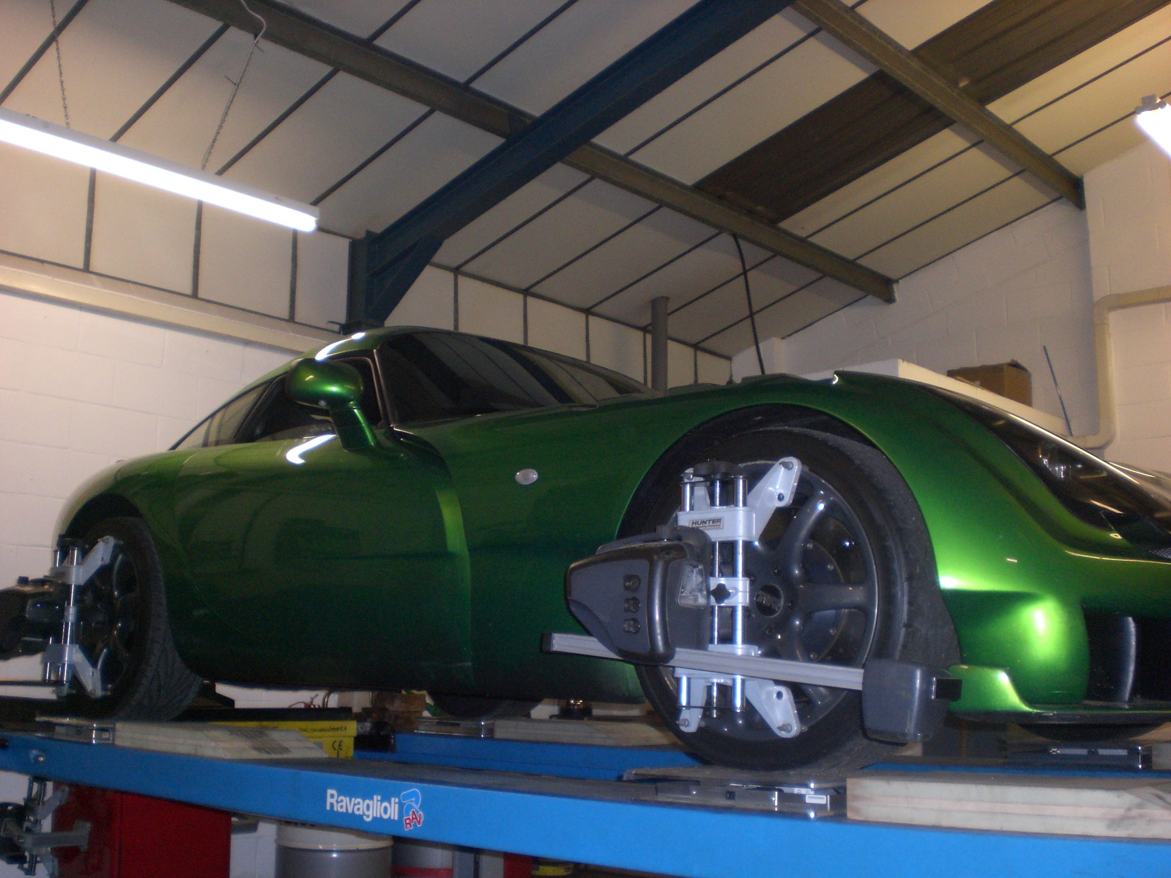 A green TVR Sagaris on the alignment ramp with alignment heads on its wheels